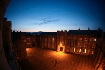 Historic building illuminated at dusk with a clear blue sky.