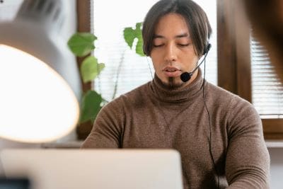 Man wearing headset working on laptop indoors.
