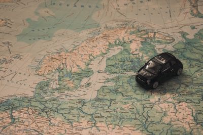 A small black car model on a vintage map background.