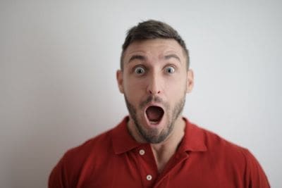 Surprised man with wide eyes and open mouth wearing a red shirt.