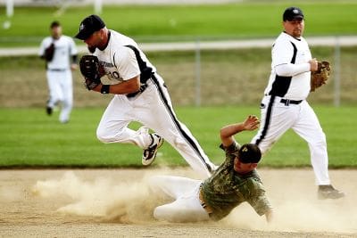 A baseball player slides into a base while the fielder catches the ball.