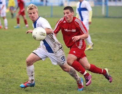Two soccer players competing intensely for the ball during a match.
