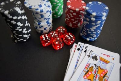 Poker chips, dice, and playing cards on a black surface.