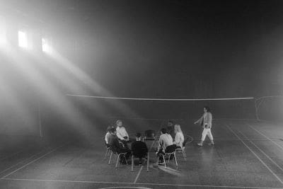 A group of people playing volleyball under bright lights at night.
