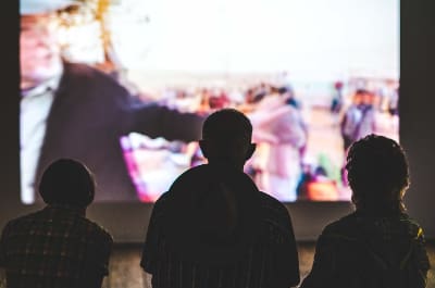 People watching a large screen in a dimly lit setting.
