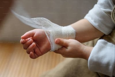 Person wrapping a wrist with a white bandage for support.