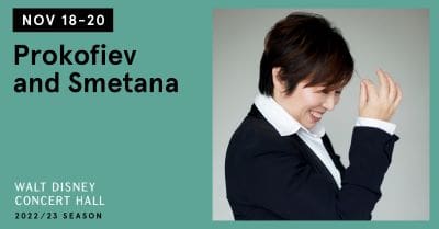 A professional woman smiling in a business suit against a teal background.