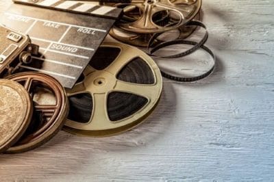 Vintage film reels and a clapperboard on a wooden surface.