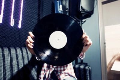 Person holding a vinyl record obscuring their face.
