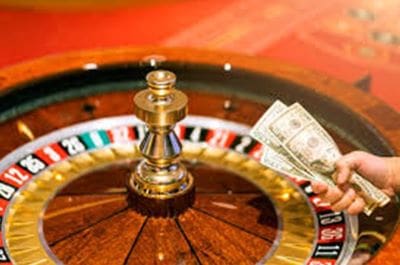 A roulette wheel with a king chess piece and dollar bills on the side.
