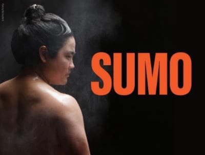 A woman with a towel on her head in a steamy environment with the word 'SUMO'.