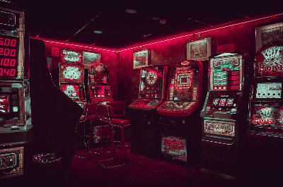 Dimly lit arcade with vintage slot machines and red neon lighting.