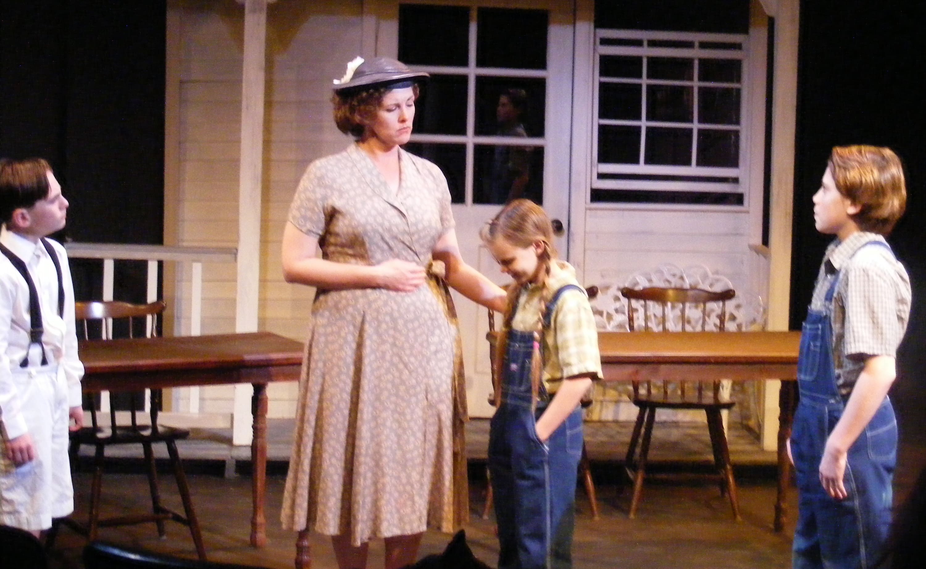 A woman and boy in vintage clothing on a stage set.