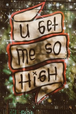 Artistic sign reads 'U get me so High' with a dreamy background.