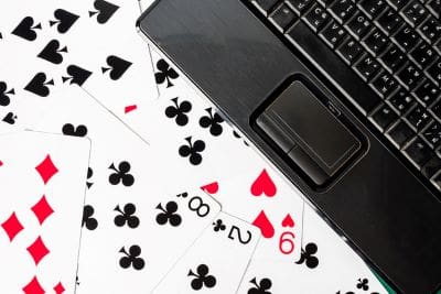 Playing cards scattered near a laptop keyboard.