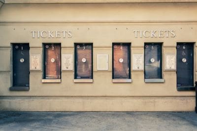 Old ticket windows with faded posters on a beige wall.