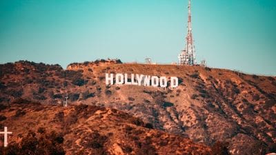 The iconic Hollywood sign on a sunny hillside under a clear blue sky.