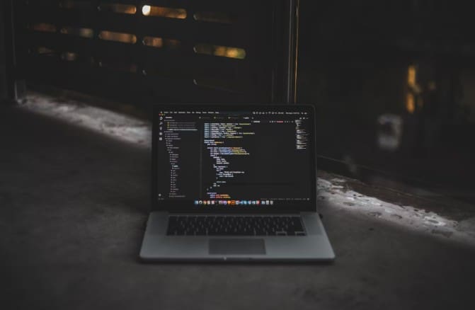 Laptop displaying code in a dimly lit room.