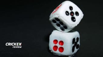 Two white dice with black and red dots on a black surface.