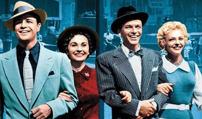 Three joyful people dressed in vintage attire, arm-in-arm, smiling brightly.