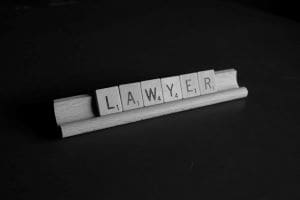 Scrabble tiles spelling 'LAWYER' on a dark surface.