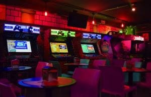 Dimly lit arcade with colorful gaming machines and cozy seating.