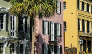 Colorful buildings with palm trees and balconies in sunlight.
