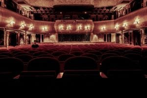 Interior view of a vintage theater with red seats and ornate decorations.