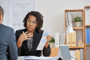 Woman in glasses holding documents and explaining in office.