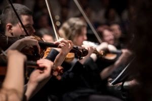 Close-up of musicians playing violins in an orchestra.