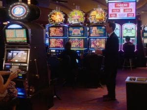People playing slot machines in a dimly lit casino.