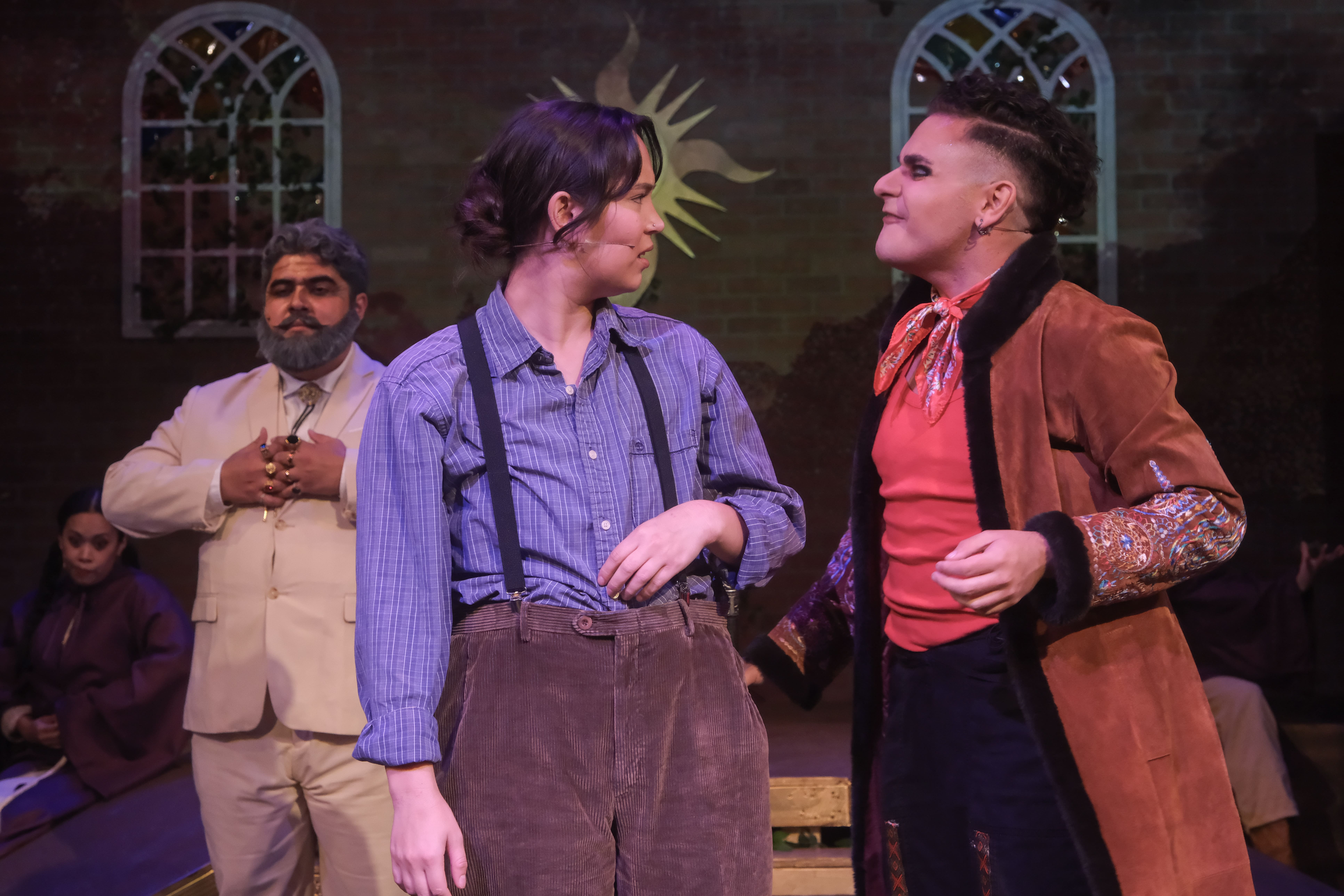 Three actors in period costumes engage in a dramatic scene on stage.