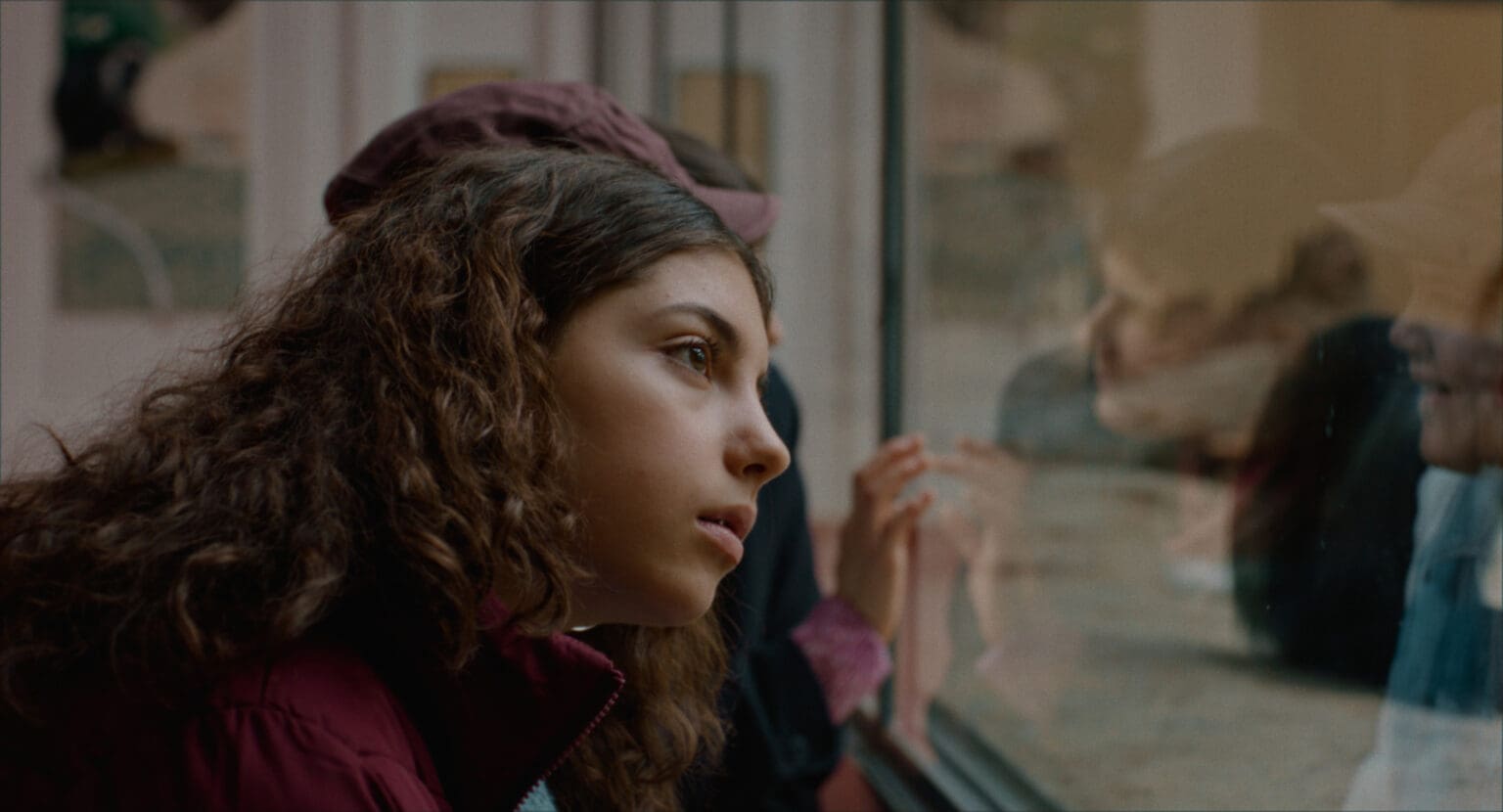 A woman gazes thoughtfully out of a window on a rainy day.