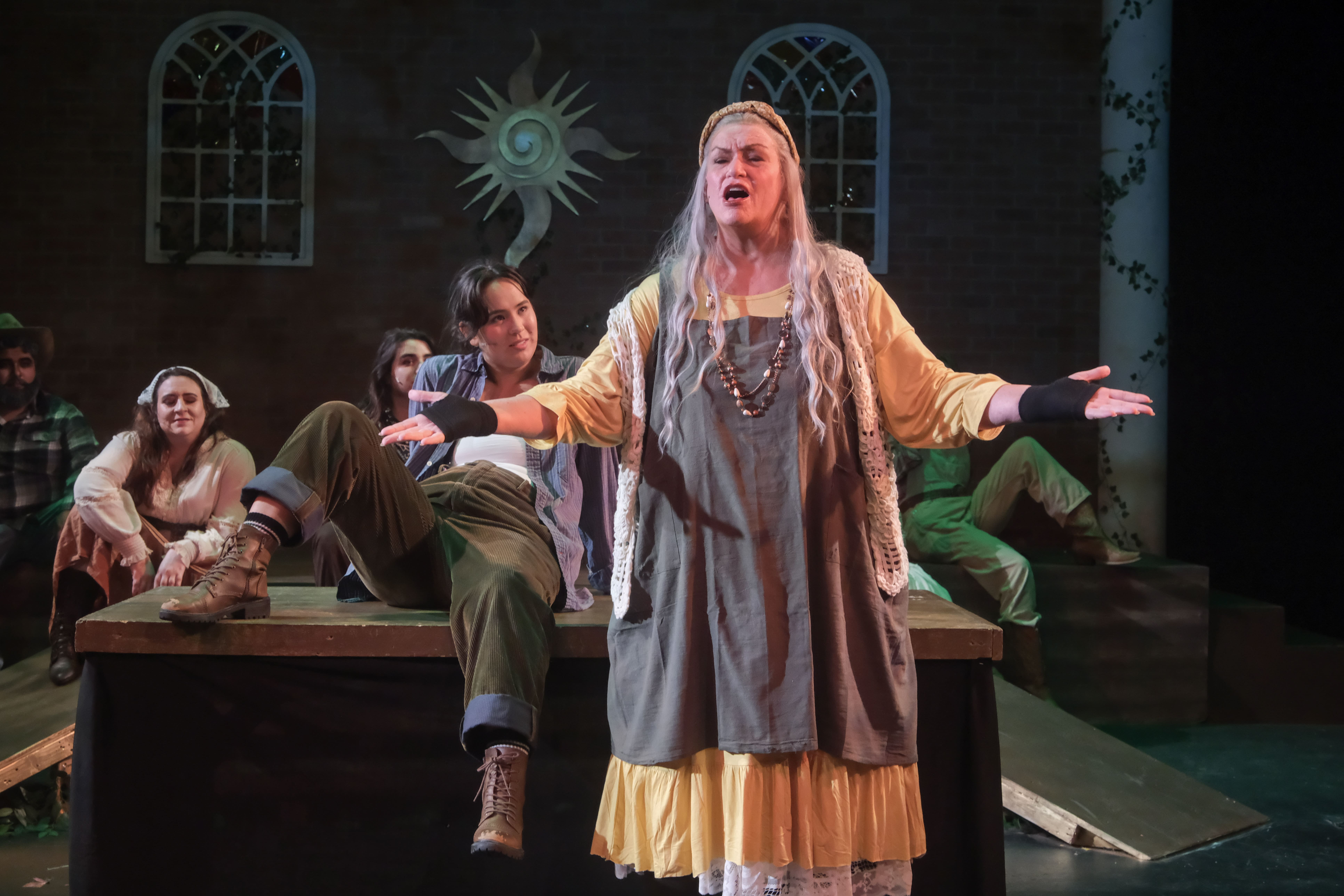 A theatrical performance with a woman singing passionately on stage.