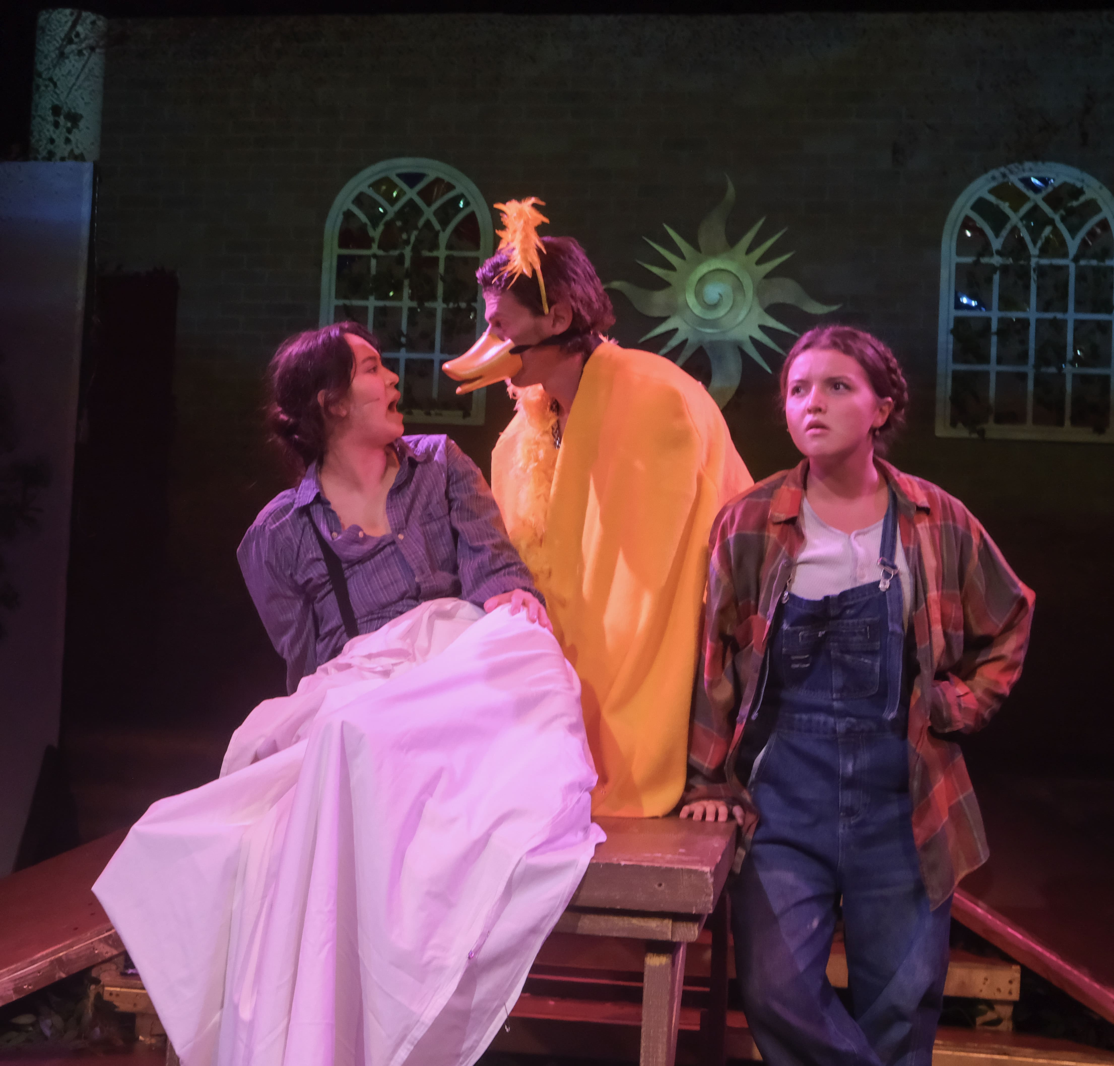 Three actors in a theatrical scene with distinct costumes and expressions.