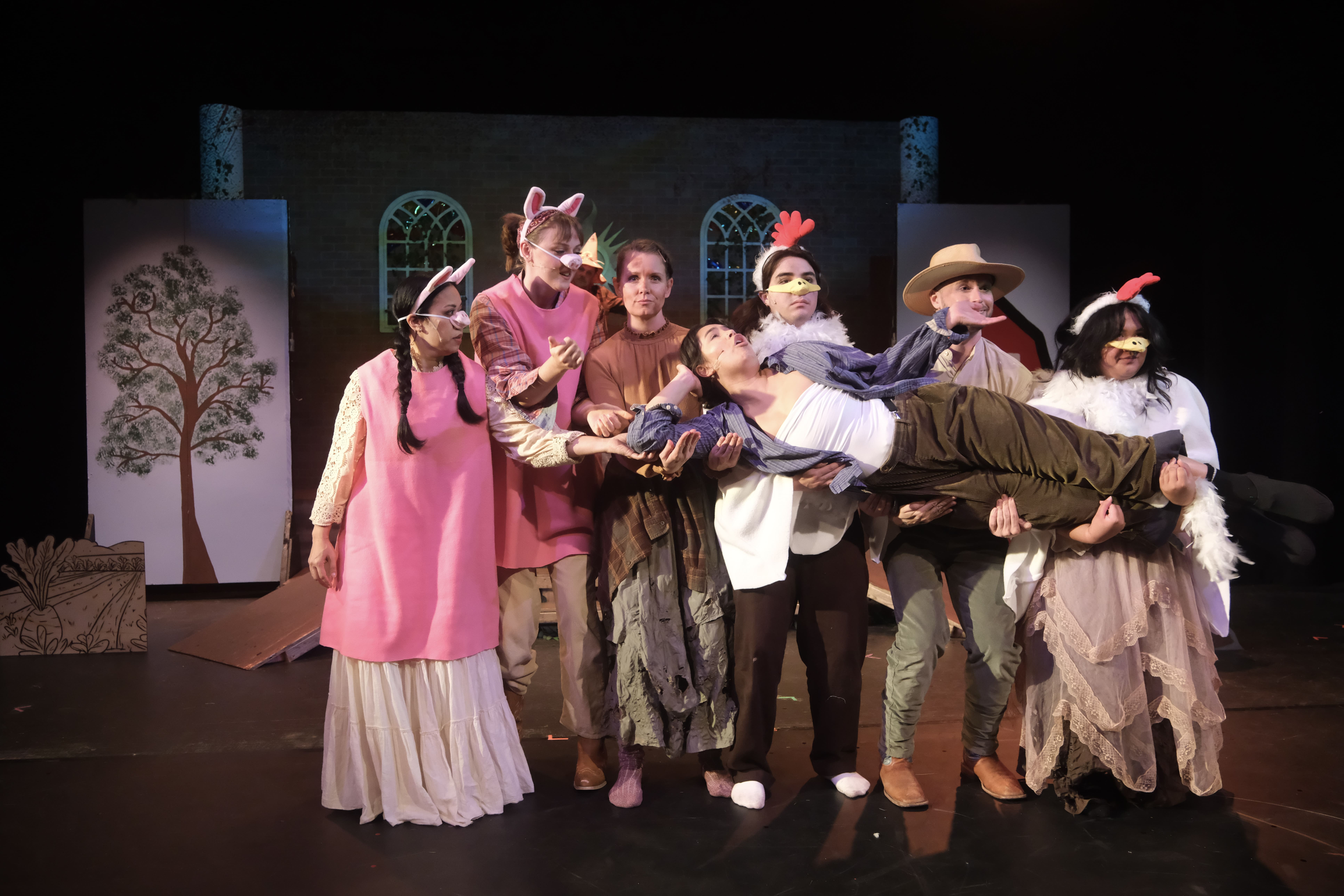 A theatrical group in costume performing a lively stage scene.