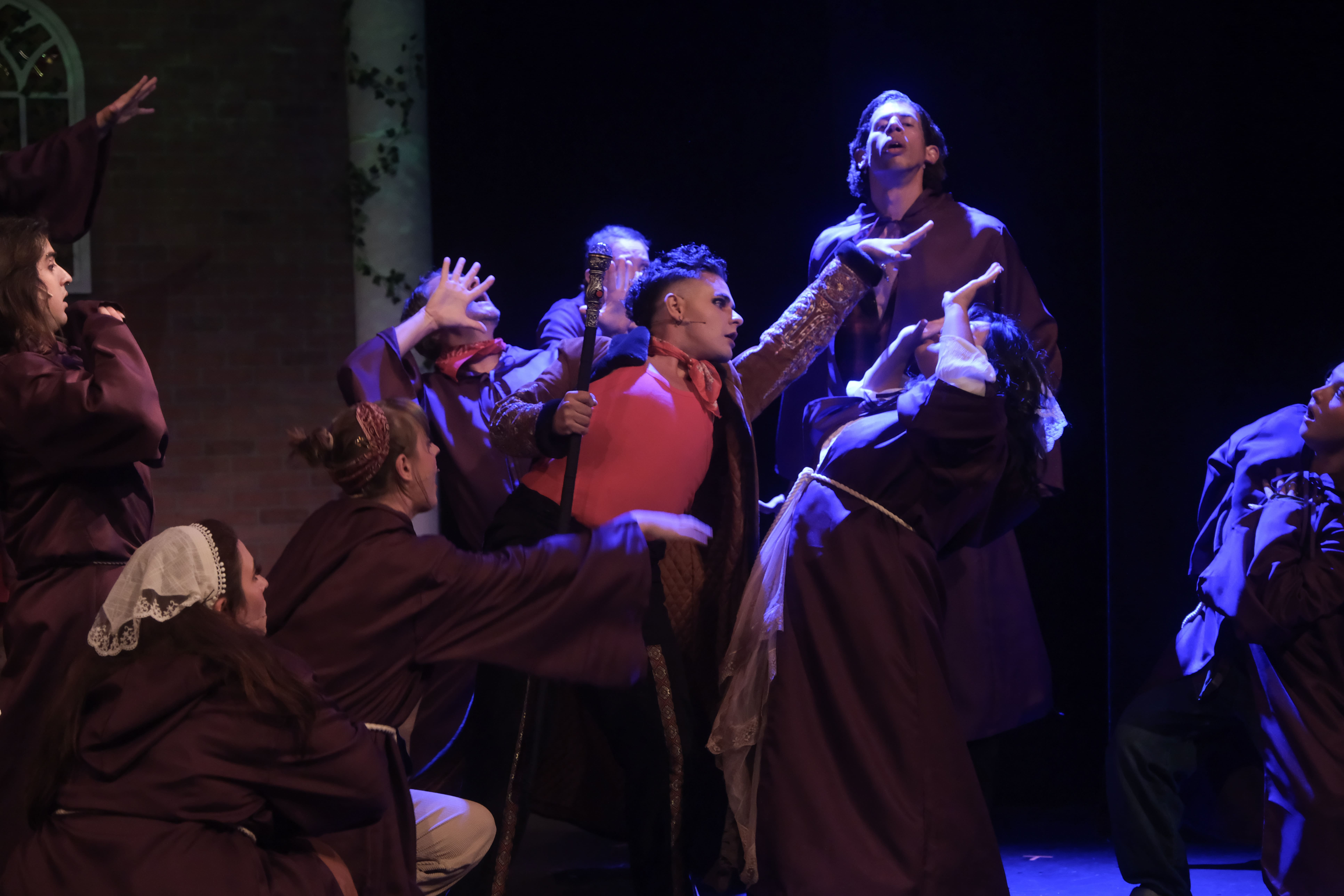 Actors in dramatic costumes perform an intense scene on stage.