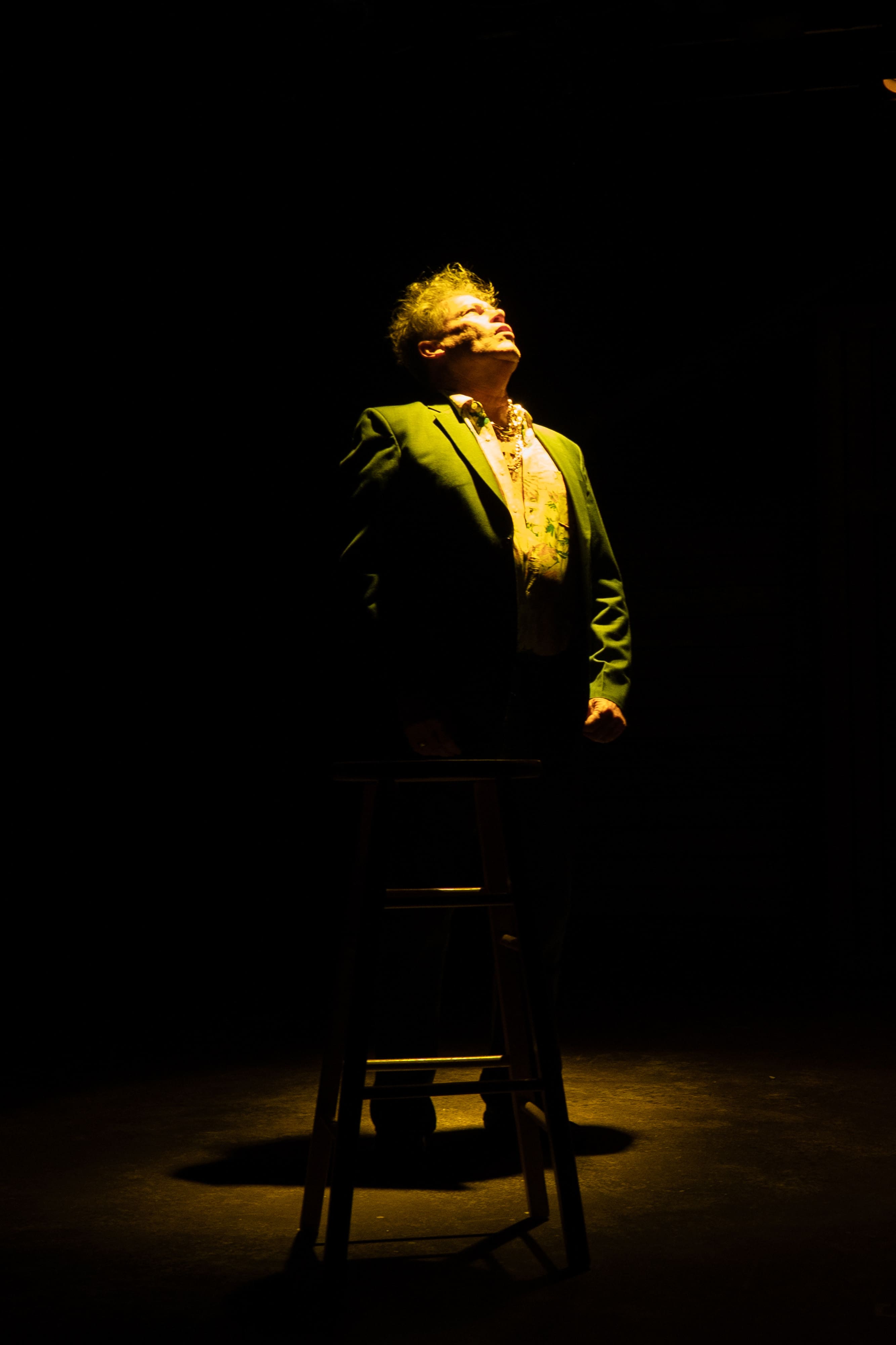 A person illuminated dramatically on stage in dark lighting.