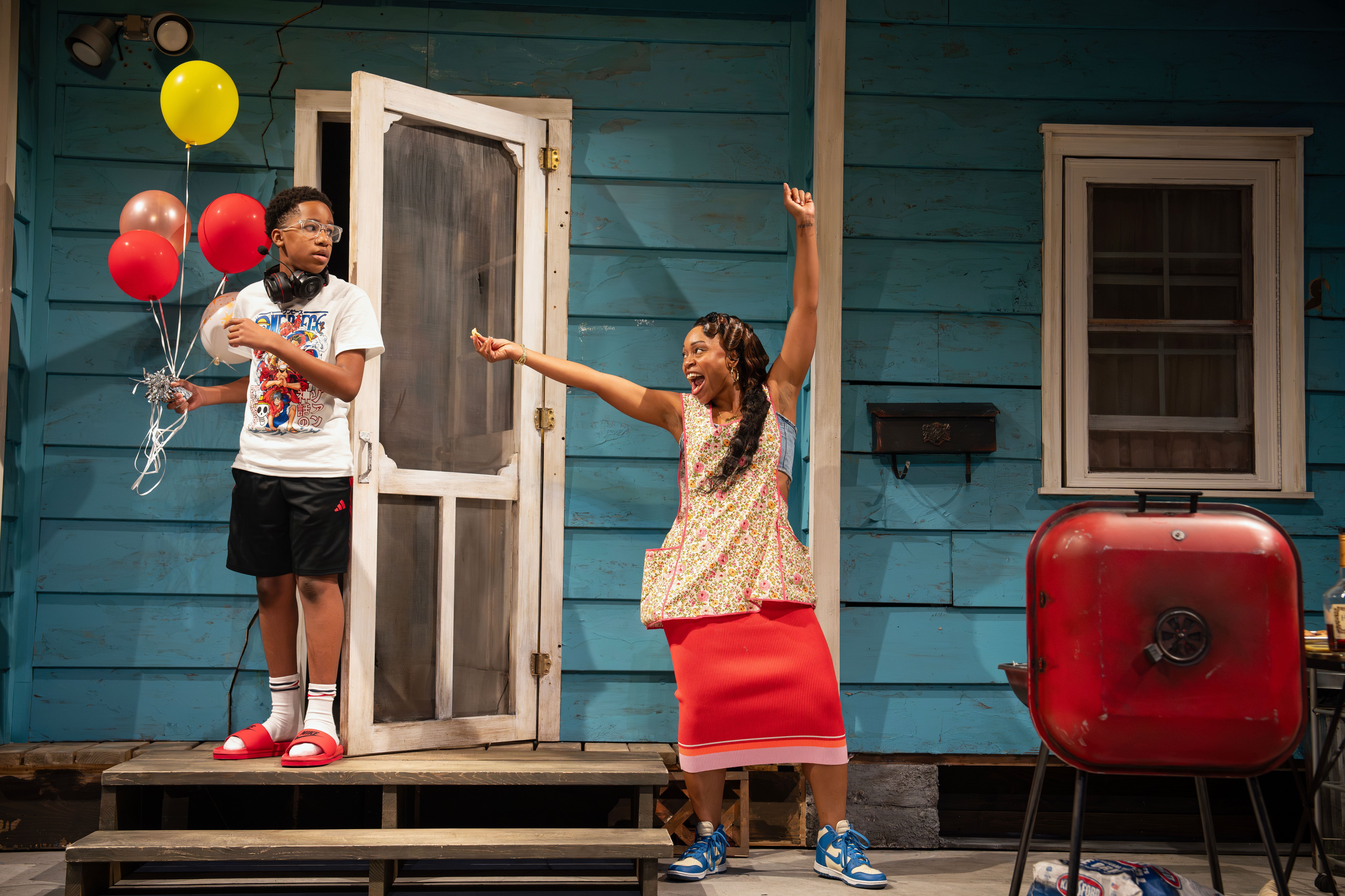 Two people joyfully interacting on a porch of a blue house.