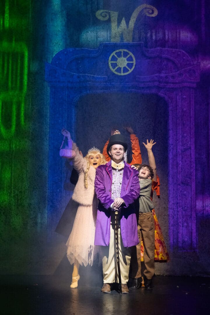 Actors perform a colorful, theatrical scene with vibrant lighting and costumes.