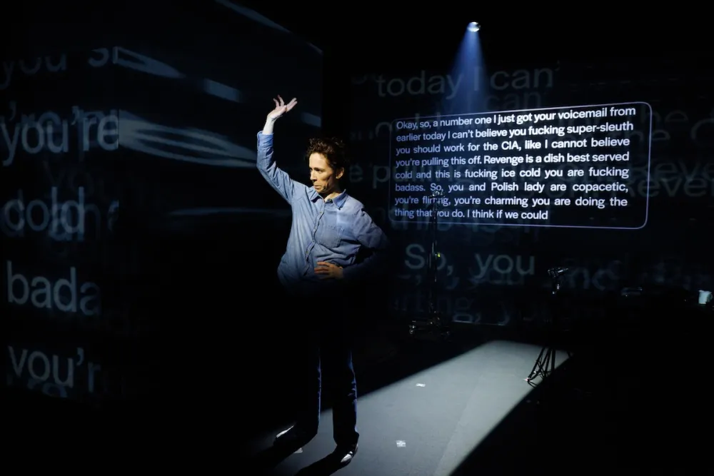 A man dances under a spotlight with text projected behind him.