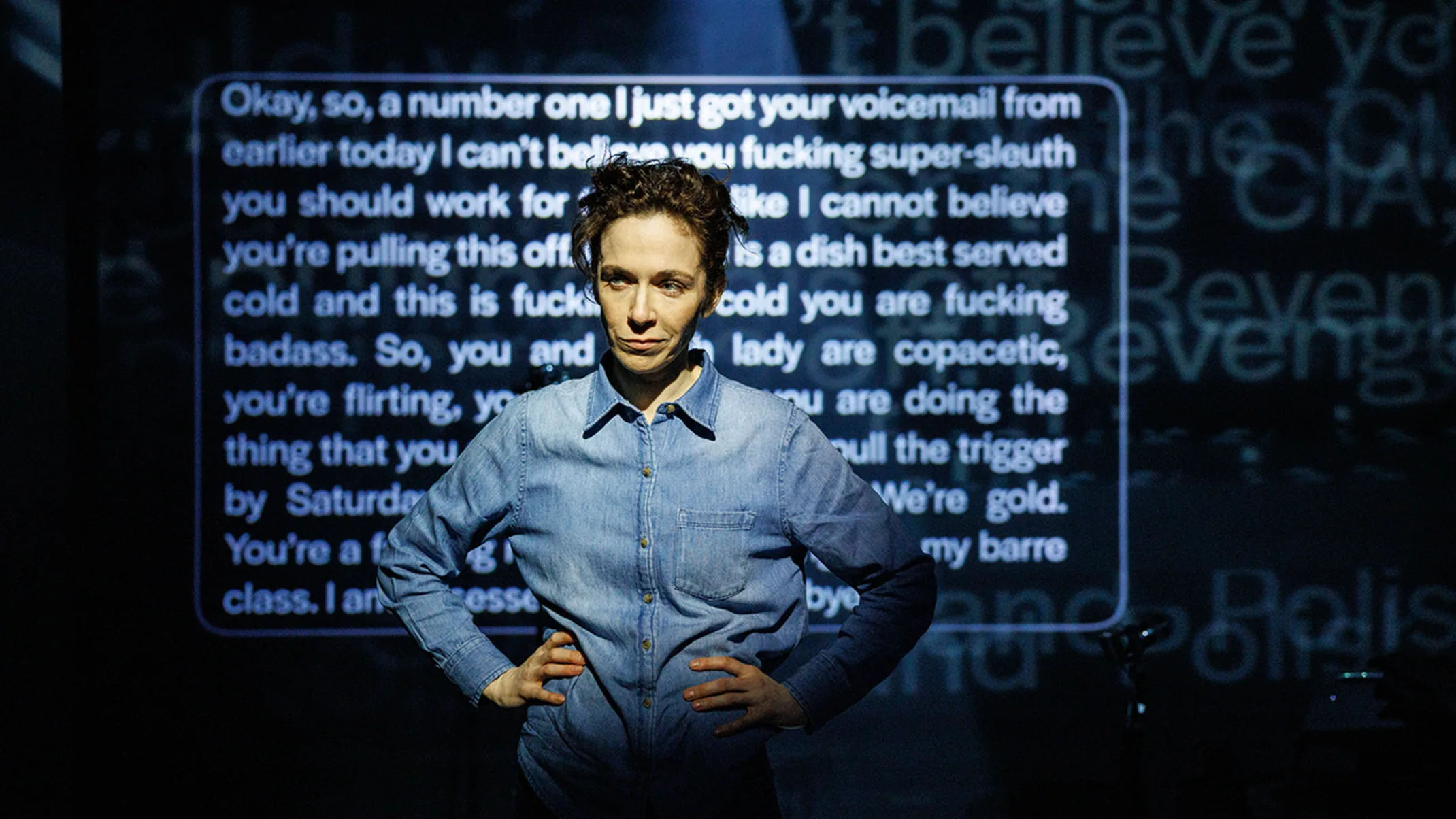 A man sitting with a serious expression, text projected behind him.