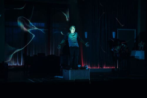A person stands in a dark room illuminated by blue and red light effects.