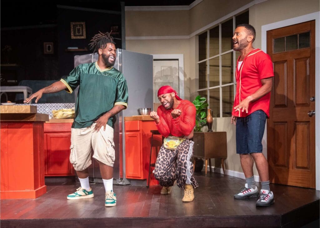 Three men engaged in a lively theatrical scene on stage.