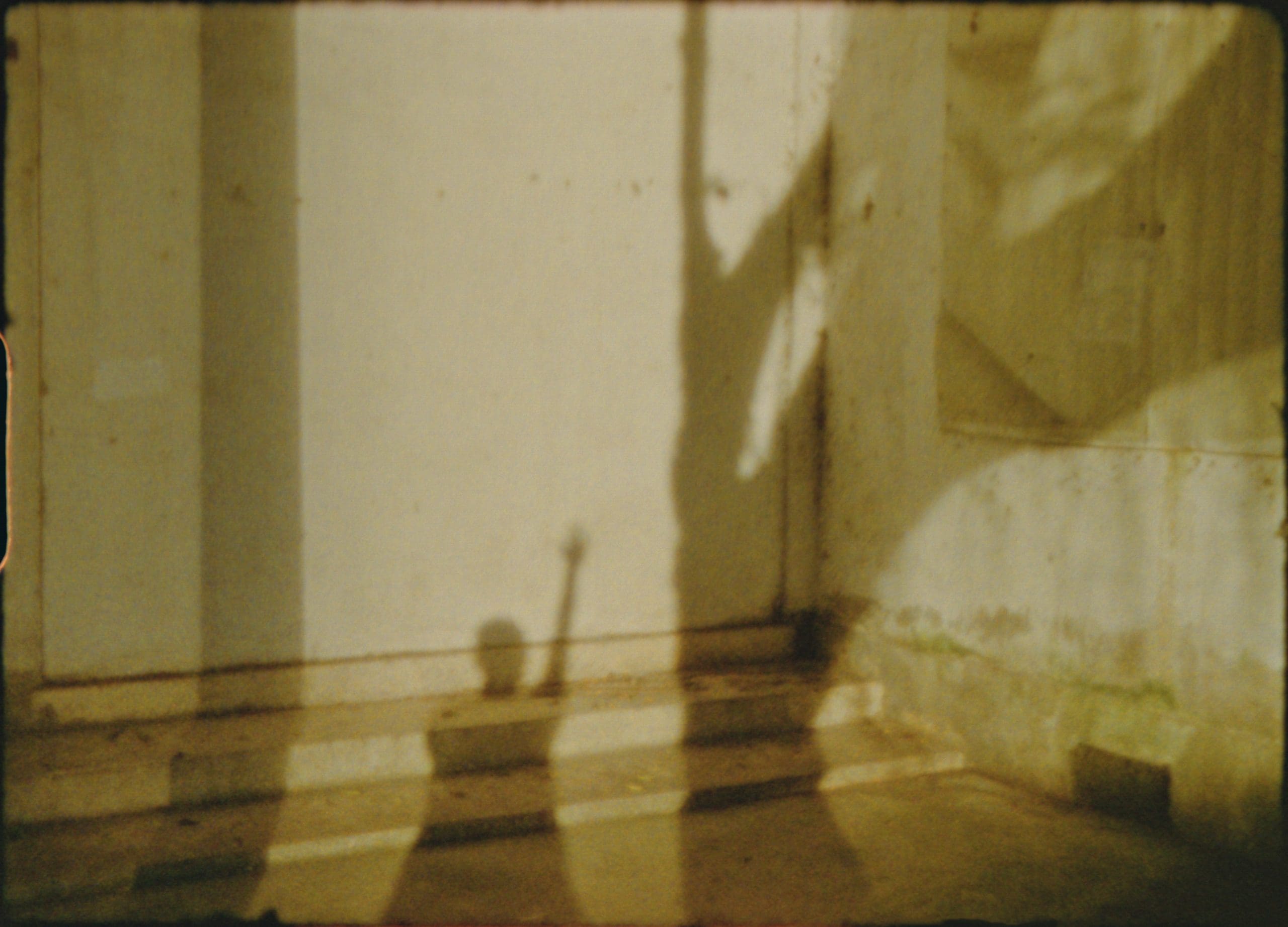 Shadow of a person raising a hand on a textured wall.