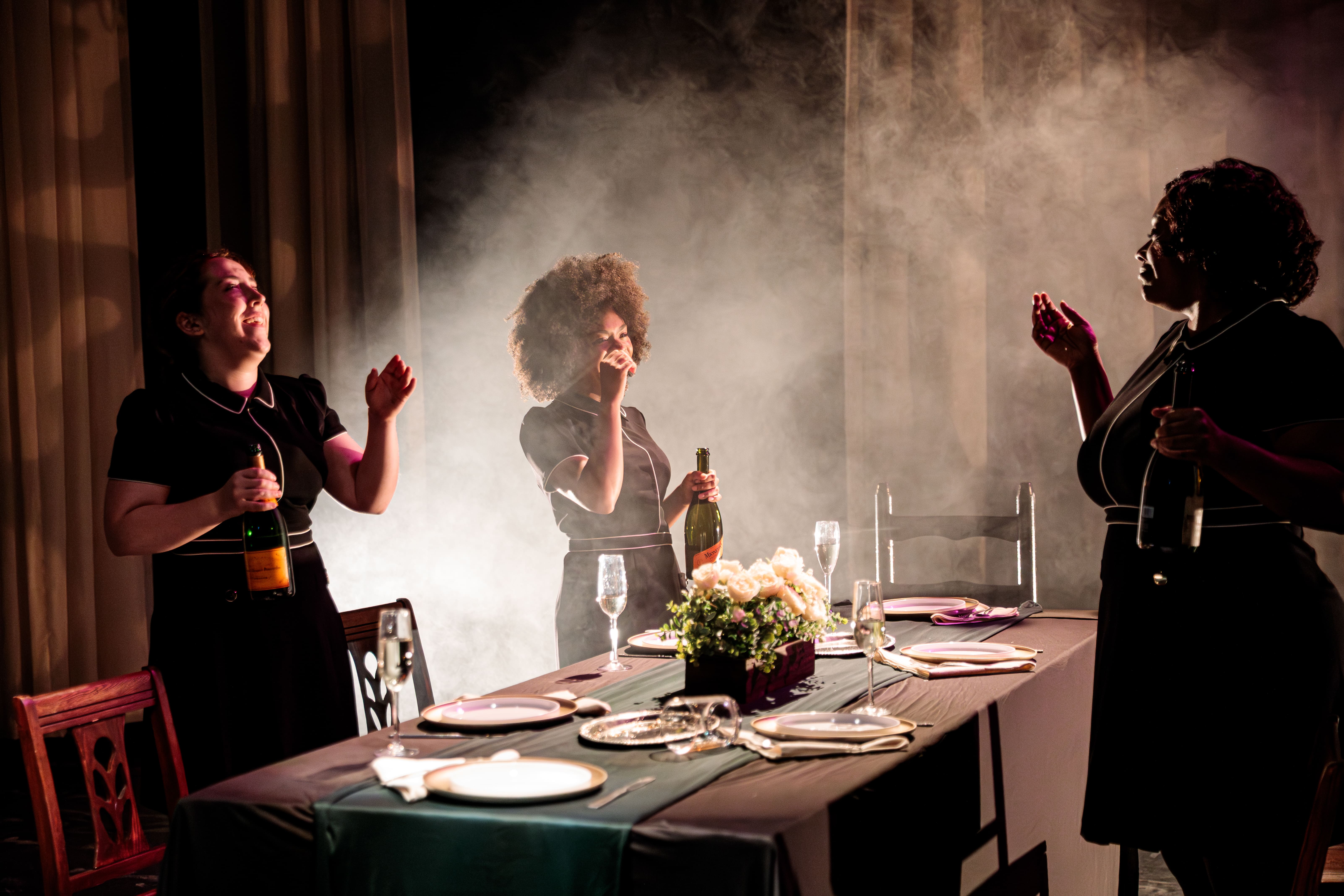 People applauding around a dinner table with a smoky atmosphere.