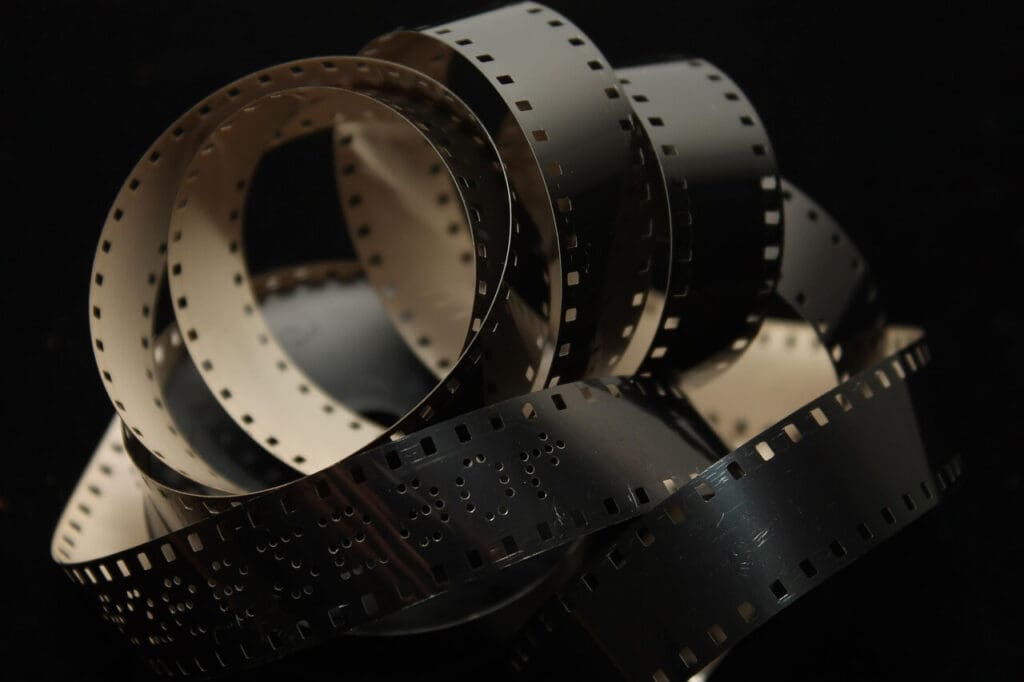 Close-up of antique film reels with perforated edges in dim light.