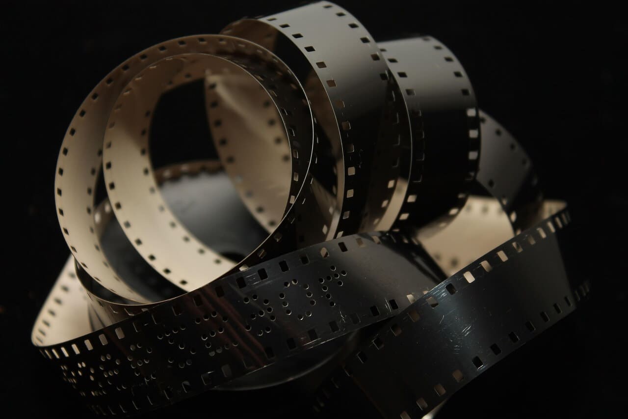 Close-up of antique film reels with perforated edges in dim light.