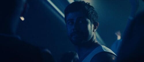 Dimly lit portrait of a man in a dark setting.