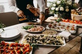 A person serving pasta at a buffet table with various dishes.